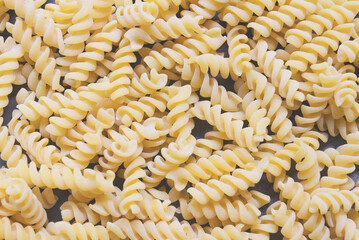 Pasta raw macaroni on wooden background, close up raw macaroni spiral pasta uncooked delicious...