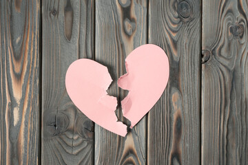 Pink torn paper heart halves laying together on dark wooden table. Broken heart, breaking up, past...