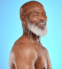 Fototapeta na wymiar Studio, water and old man in a shower cleaning his face or body for skincare beauty or wellness on a blue background. Smile, healthy or happy elderly male model washing or relaxing with mock up space
