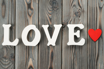 Close up of white plastic or wooden letters forming word love, red paper heart near the word. Love...