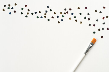 Paintbrush draw and mark small colorful paper hearts on white background. Decorative foil and paper elements for decoration. Glowing and shining art. Valentines day make up. Top view, copy space