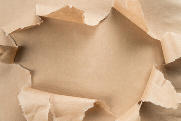 Beige crumpled packaging paper unwrapping from center, ragged paper. Unpacking and bursting from the center. Presents for holidays. Sustainable resource, eco friendly. Overlay, copy space, top view