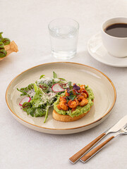 Portion of avocado toast with grilled shrimp and salad