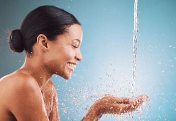 Skincare, health and black woman with water splash, wellness and hygiene against a blue studio...