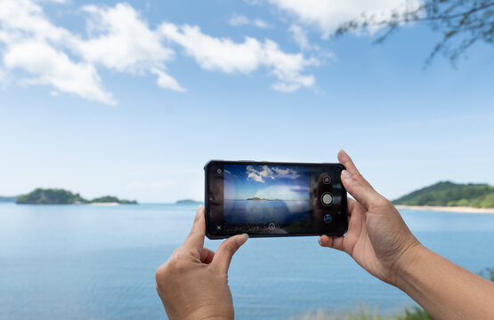 Taking photos on the mobile phone, Take Photos of the seascape view, taking Photo Vacation time to the Seascape, Hand on Mobile take Sea scape view.  