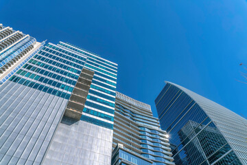 Looking up at modern glass buildings with windows that reflects the city views