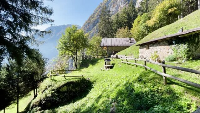 Static wide shot of a beautiful scenery in the Italian Alps, S&uuml;dtirol. Beautiful weather, mountains with trees in the background. Small hut in the foreground.