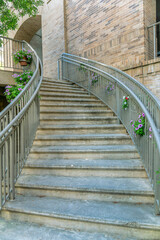 Curving outdoor stairway with steel rails decorated with hanging flower plants