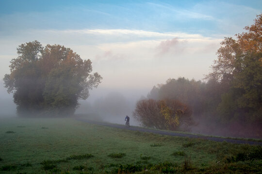 Ein einsamer Radfahrer bahnt sich seinen Weg durch den Morgennebel an einem Fluß