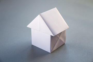 White paper house origami isolated on a grey background