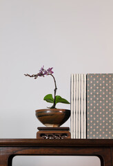 Purple orchid, Chinese antique ceramic and traditional style book on wooden table against white wall