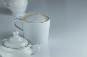 Cup of coffee with milk on white table