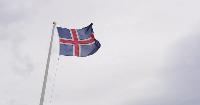 Flag of Iceland on flagpole. Waving Icelandic Flag Against Sky with Clouds. National Flag of Iceland. Video for tourism and Icelandic Republic Day, National Day.