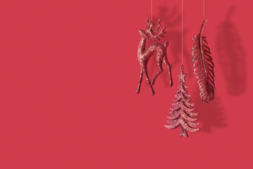 Christmas New Year banner with XMAS tree, deer and feather glitter toys on red background with copy space
