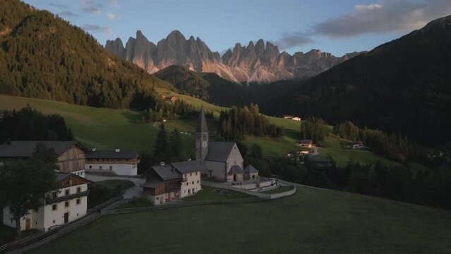 Iconic Santa Maddalena Church in the Dolomites. Famous Church of St Magdalena, with a beautiful backdrop in soft evening light. Italian Dolomites Epic Landscape footage by drone in 4k, 24fps.
