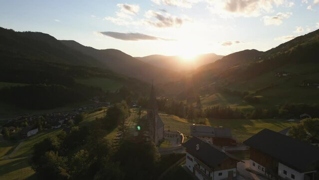 Sunset in the Dolomites, Santa Maddalena Village. Famous St Magdalena Church in Italian Mountains. Golden hour landscape with lens flare, captured by drone in 4k, 24fps. Beautiful scenery in Italy.