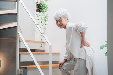 階段で腰痛に苦しむ高齢の女性