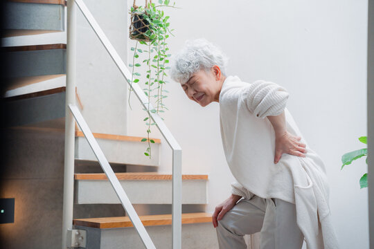 階段で腰痛に苦しむ高齢の女性