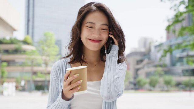 Charming young asian business lady walking in the urban street talking on the mobile phone relax happy office lady in city slow motion