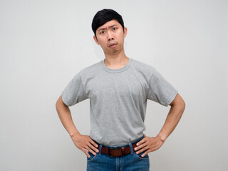 Asian man grey shirt stand hands at waist feels doubt at face isolated
