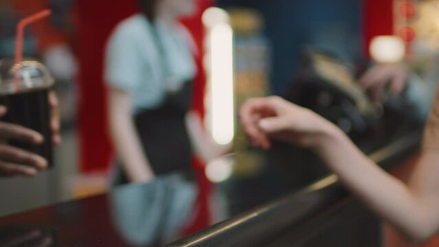 Selective focus shot of unrecognizable people buying popcorn and fizzy drinks at cinema