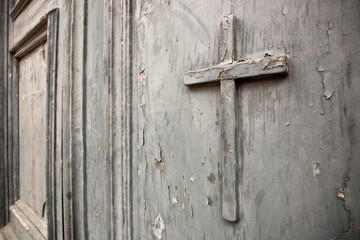 Old closed church doorway with small wooden religious cross
