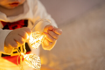 The boy holds a Christmas garland in his hands