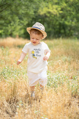 A kid in a straw hat runs across the field in summer