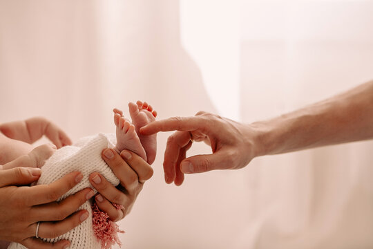 Close up of hands of anonymous mother and father, petting little baby, touching his bare foots