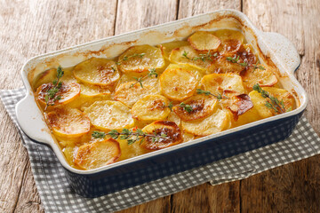 Scalloped potatoes, potato casserole with the addition of herbs, onion and garlic in a ceramic...