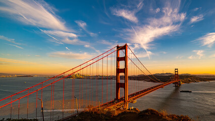 Fototapeta na wymiar Golden Gate Bridge at sunset with boat entering San Francisco Bay
