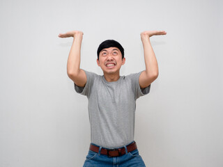 Young asian man grey shirt gesture carry something above himself feels heavy isolated