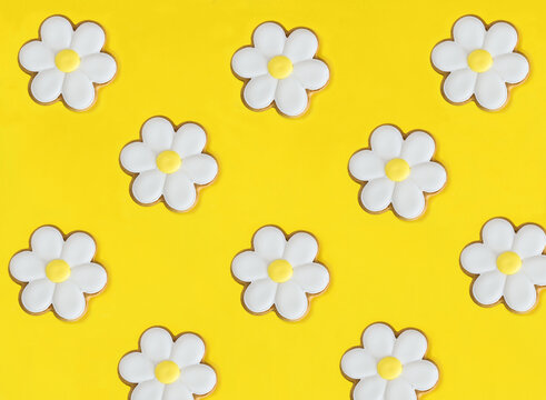Chamomile in the form of gingerbread on the yellow background. Flat lay. Pattern. Top view.