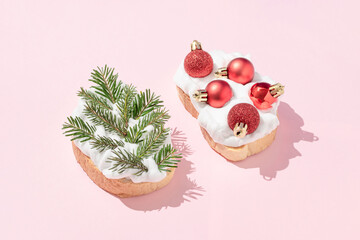 Christmas tree branches and red baubles sandwiches on bright pink background. Minimal New Year or...