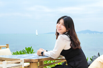 Happy woman smiling during breakfast summer vacation at sea. Beautiful lady relaxing at beach while siting beside the beach breakfast