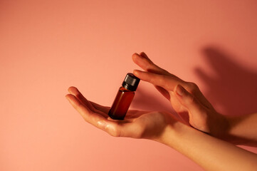 Brown bottle in beautiful hands on a peachy light background.