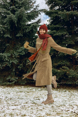 Fototapeta premium Full length of happy woman with cup of takeaway coffee having fun in snowy winter park and looking at camera 