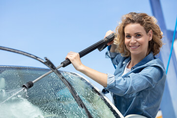 portrait of smiling woman washing car windscreen at yard