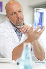 scientist at work in his lab looking at violet liquid