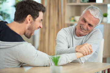 Obraz premium old father and his son are playing arm wrestle