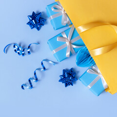 Many gifts for the holidays concept. Holiday gift boxes with bows in a gift bag on a color background