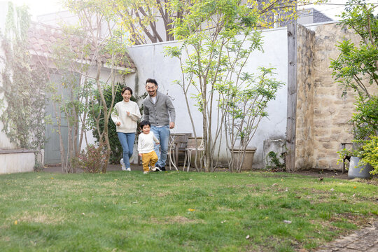 Image of Asian child and family running around in yard or park, wide angle