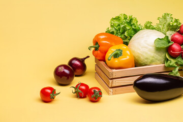 Set of summer healthy seasonal vegetables on a bright yellow background in a wooden box. eggplant, cabbage, tomatoes, regis, onions, bell peppers and lettuce.Advertising. Wellness. Copy space.