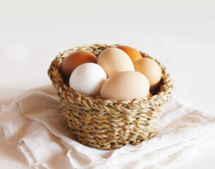 Fresh chicken eggs in a basket on a light background