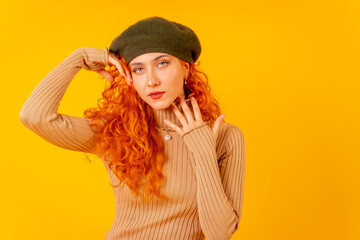 Red-haired woman in beret in studio on a yellow background, copy space, portrait pretty model