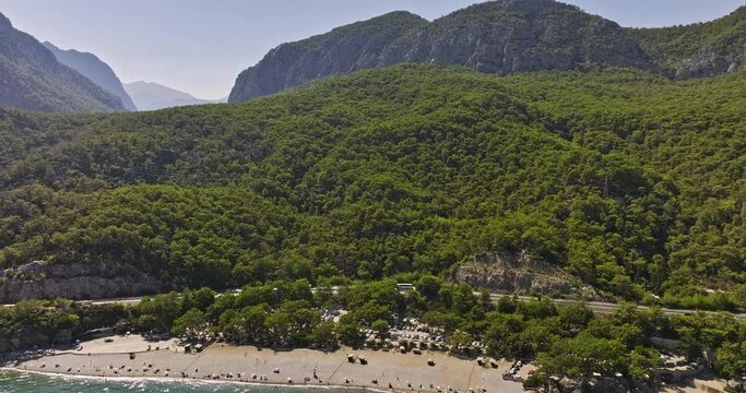 Antalya Turkey Aerial v50 flyover topman beach with people swimming in the sea, tilt up reveal t&uuml;nek tepe mountain ranges, coastal woodland with dense vegetations - Shot with Mavic 3 Cine - July 2022