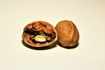 Opened walnut stems next to a whole walnut close-up on a white background