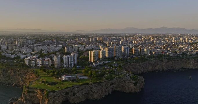 Antalya Turkey Aerial v19 panning view along coastline capturing urban park and modern cityscape of fener residential neighborhood at beautiful sunset golden hour - Shot with Mavic 3 Cine - July 2022