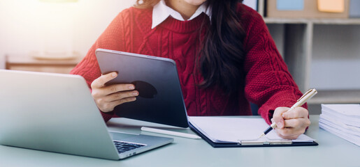 Young business woman sitting in office at table and using smartphone. On desk is laptop and tablet computer, on screen charts and graphs. Woman analyzing data. Student learning online.