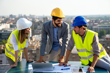 Construction concept. Engineers and architects working at construction site with blueprint